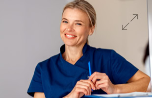 Eine lächelnde Person in blauer Arbeitskleidung hält einen Stift.