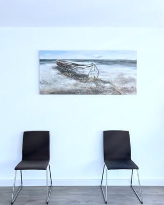 zwei stuehle unterm ruderboot mit jukapalme zur rechten