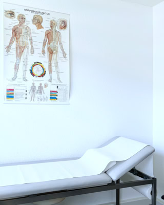 heller untersuchungsraum mit patientenliege und akupunktur poster an der weissen wand